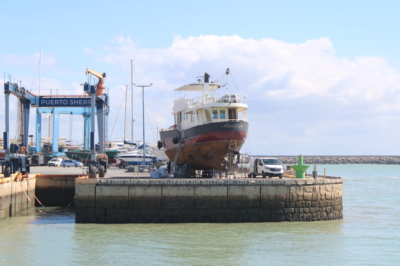 A ship in dry dock at Puerto Sherry marina, Spain, showcasing maritime maintenance.