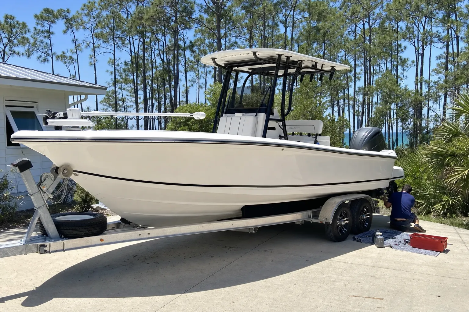 Technician servicing outboard motor on center console boat in Panama City residential driveway.
